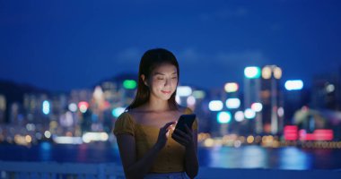 Kadın geceleri şehirdeki akıllı telefonlara bakıyor.