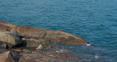 Kıyı şeridindeki kaya ve taşın üzerinde deniz dalgaları