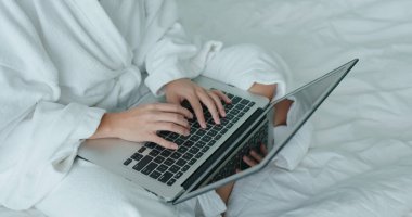 Karantina döneminde otel odasında dizüstü bilgisayarda çalışan bir kadın.