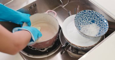 Kadın mutfakta bulaşık yıkıyor.