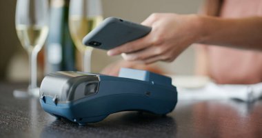 Kadın cep telefonuyla ödeme yapıyor.