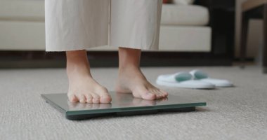 Kadın ağırlığını ölçmek için tartıda duruyor. 