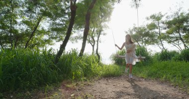 Gün batımında bir kadın köpeğiyle sallanıyor.