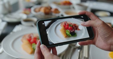 Kadın çanakların fotoğrafını çekmek için cep telefonu kullanıyor.