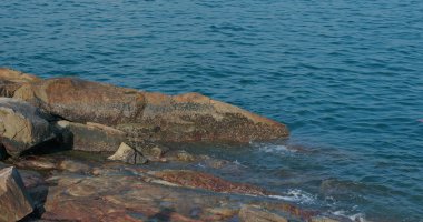 Kıyı şeridindeki kaya ve taşın üzerinde deniz dalgaları