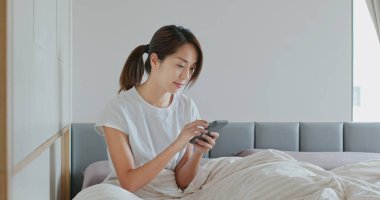 Kadın yatağında cep telefonu kullanıyor