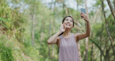 Parkta cep telefonuyla kadın konuşması.