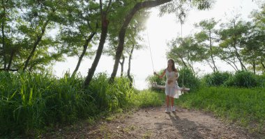 Gün batımında bir kadın köpeğiyle sallanıyor.