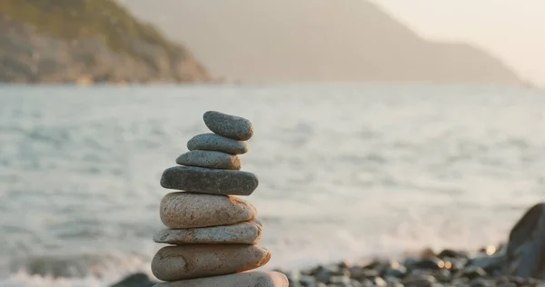 Balanced pebble pyramid on the beach at sunset