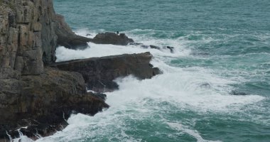 Deniz dalgaları adada kayalara çarpıyor.