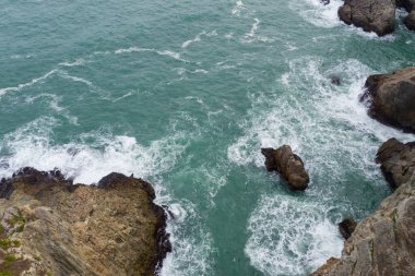 Deniz suyu dalgalarının yukarıdan görünüşü kayalara çarpıyor.