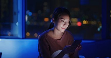 Gece yatakta cep telefonu kullanan bir kadın.