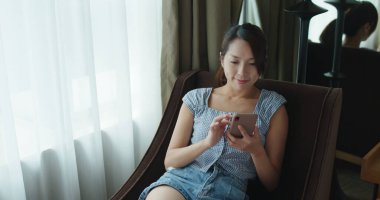 Kadın akıllı telefon kullanır ve kanepeye oturur.