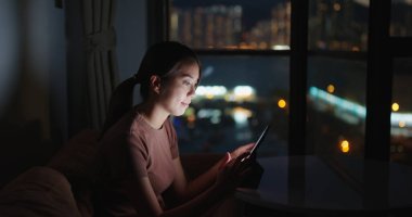 Evdeki tablet bilgisayarda okuyan kadın