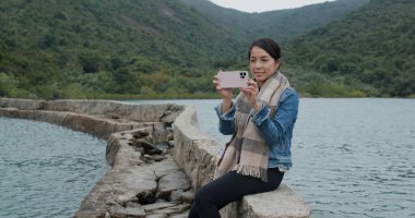 Kadın fotoğraf çekmek için cep telefonu kullanıyor.