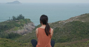 Kadın dağın tepesinde oturuyor.