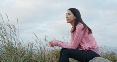 Kadın dağda oturur ve manzaranın tadını çıkarır.