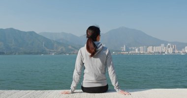 Kadın rıhtımdaki deniz manzarasının keyfini çıkar.