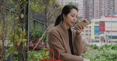 Kadın parktaki cep telefonundan sesli mesaj gönderiyor.