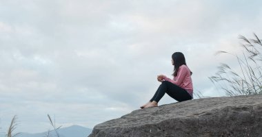 Kadın dağın tepesinde oturuyor.