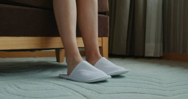 Otel odasında terlik giyen bir kadın.
