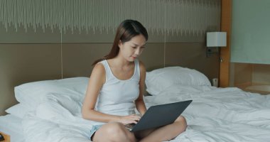 Kadın yatakta bilgisayarla çalışıyor.