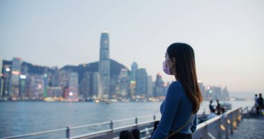 Kadınlar gün batımında Hong Kong manzarasının tadını çıkarırlar.