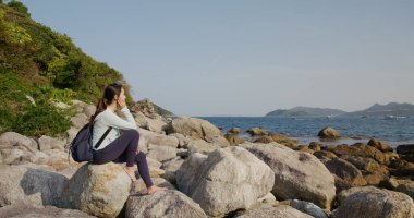 Kırsal kesimdeki kayalarda oturan kadın.