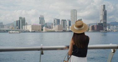 Kadın gün batımında Hong Kong şehrine bak.