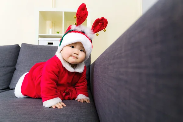 Baby girl with christmas dressing and creeping on sofa — Stock Photo, Image