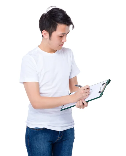 Young man writes on clipboard — Stock Photo, Image