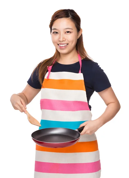 Домохозяйка готовит с жареной сковородкой и деревянным ковшем — стоковое фото