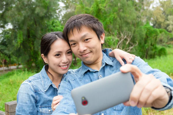 Asijský pár užívání selfie v parku — Stock fotografie