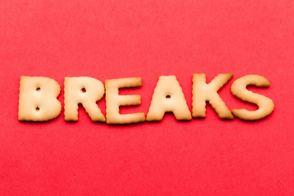 Word breaks biscuit over the red background — Stock fotografie