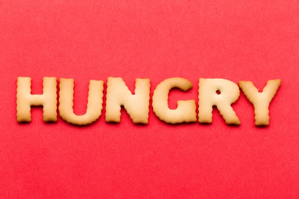 Word hungry cookie over the red background — 图库照片