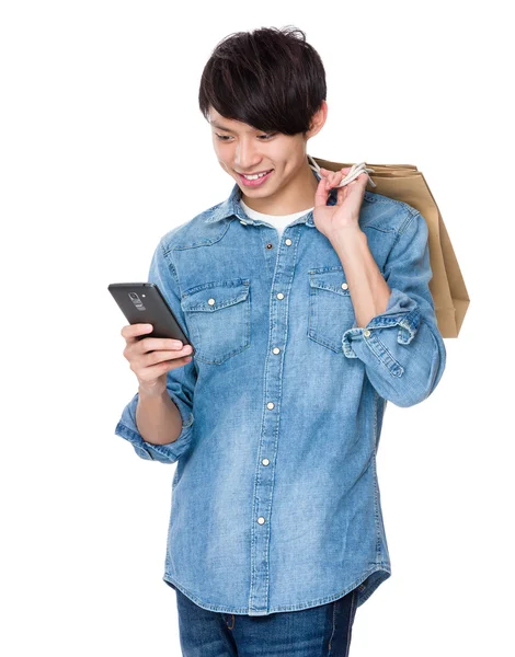 Jeune homme tenir sac à provisions et regarder le téléphone portable — Photo