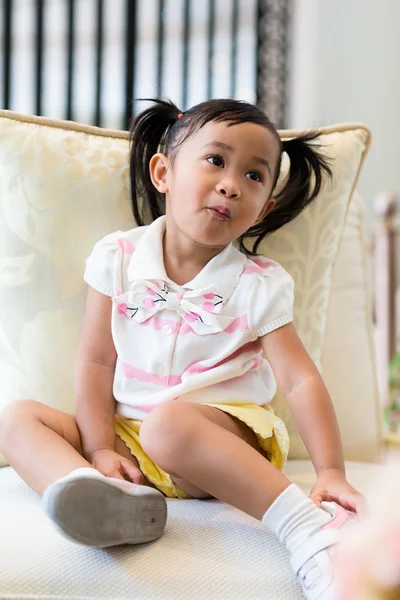 Милая маленькая девочка сидит на диване — стоковое фото