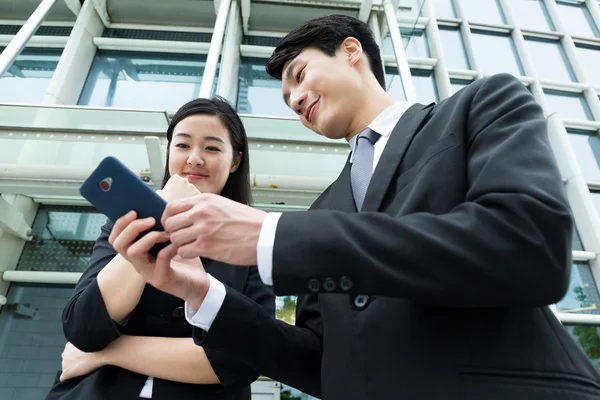 Asiático socios de negocios leer algo en el celular en al aire libre —  Fotos de Stock