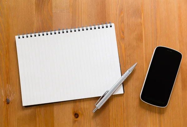 Mobile phone on desk with blank handbook — Stock Photo, Image