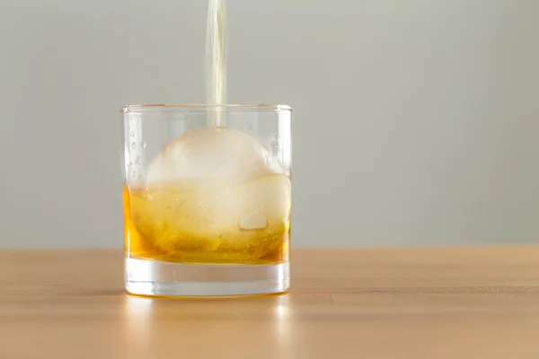 Whiskey drink on table with ice cube