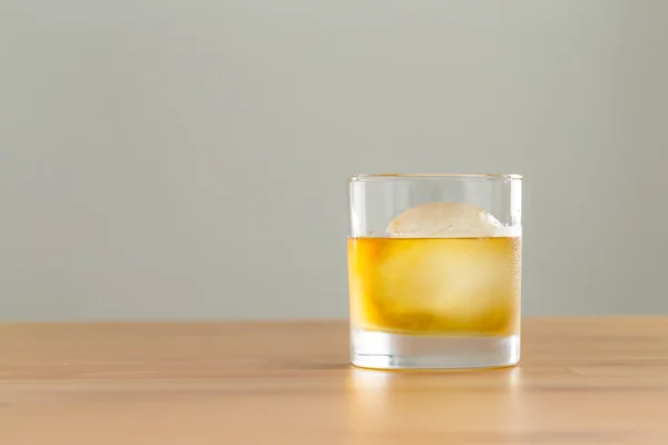 Bebida de uísque na mesa com cubo de gelo — Fotografia de Stock