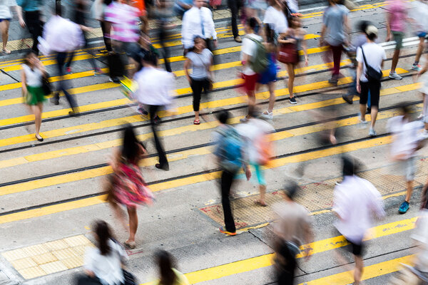 Motion blurred pedestrians crossing Hong Kong street 