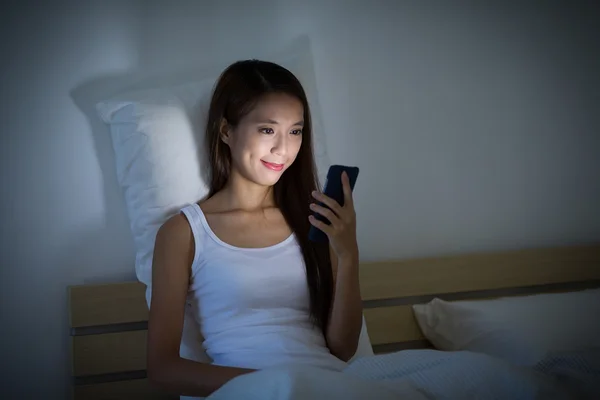 Kobieta z telefonem komórkowym na łóżku — Zdjęcie stockowe