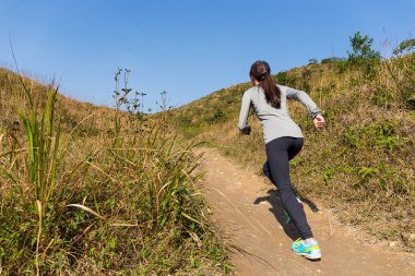 Spor kadını dağda koşuyor.