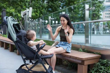 Genç anne şehirde bebek arabasında bebekle eğleniyor.