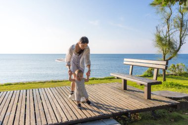 Anne ve baba, bebeğin suya ilk adımlarını atmasına yardım ediyor.