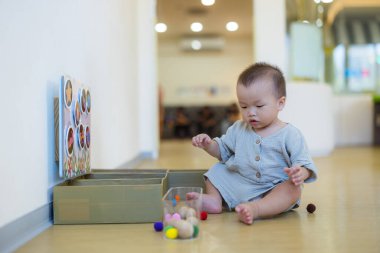 Küçük oyun evinde oturup oynayan şirin bir bebek.