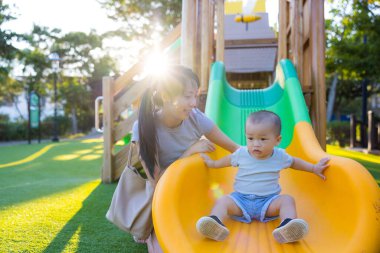 Anne ve bebek park kaydırağında birlikte oynuyor.