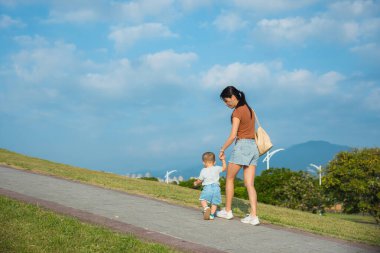 Anne oğluyla parkta yürüyor.
