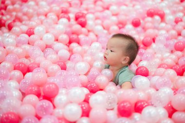 Mutlu bebek pembe top havuzunda eğleniyor